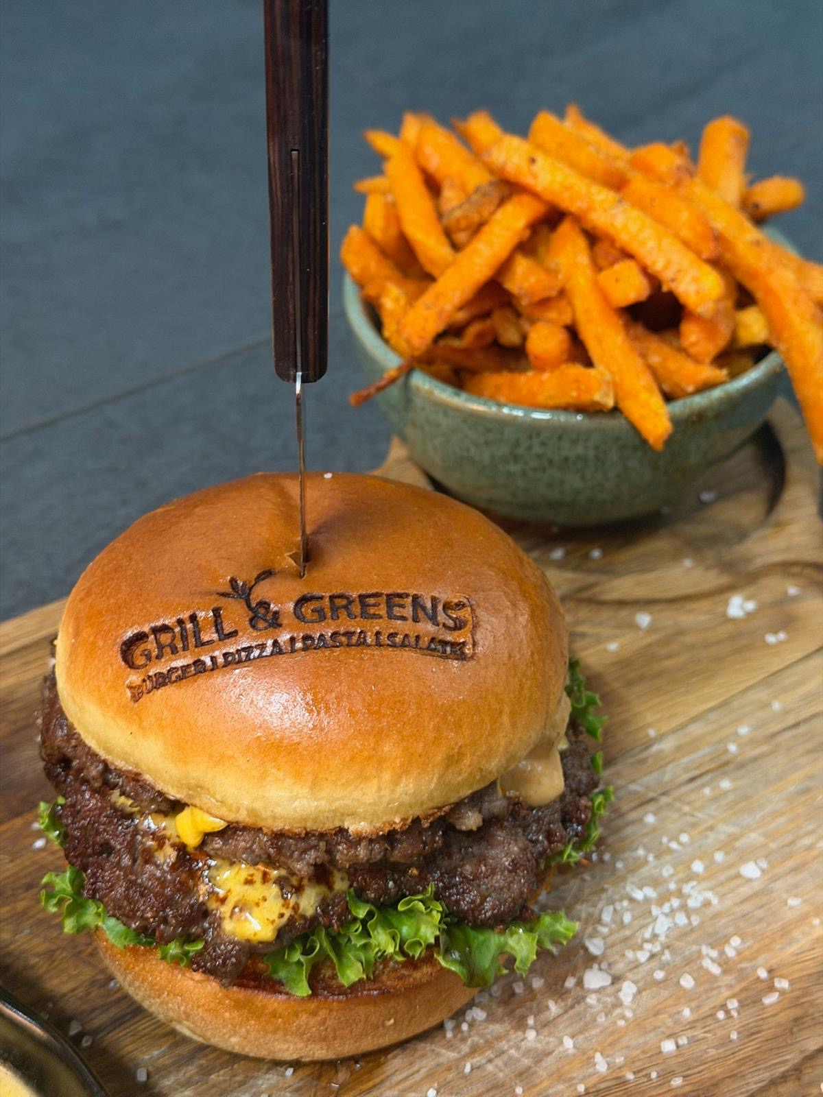 Burger mit GRILL AND GREENS Logo auf dem Brötchen